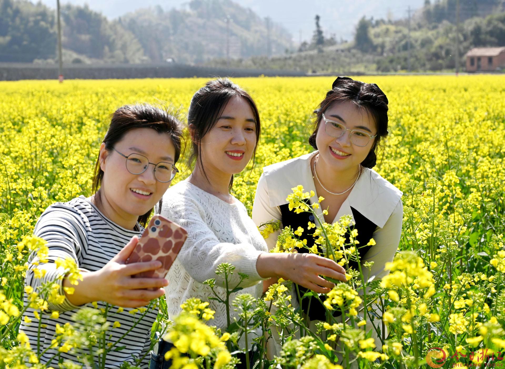 3月10日，游客在武义县下杨村原俞源砖瓦厂取土场新垦造的百亩油菜花海游览拍照。